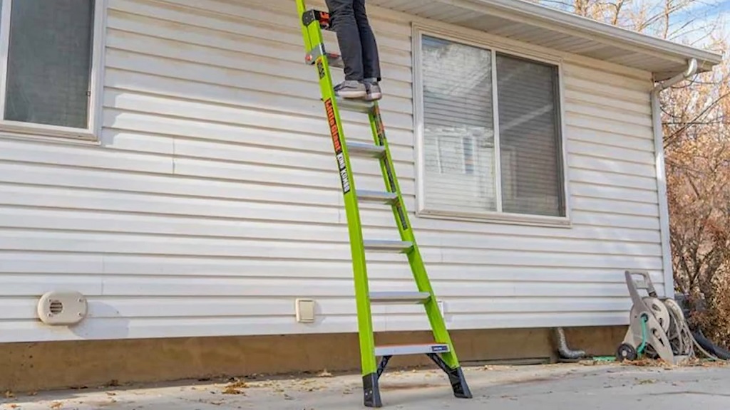 Homeowner using a ladder for gutter cleaning along the roofline