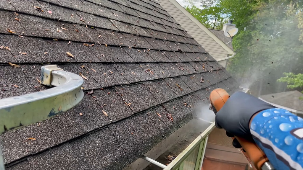 Power washer being used for gutter cleaning on a residential roof