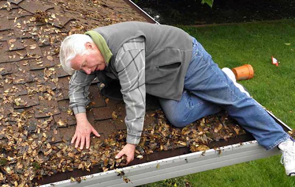 Unsafe attempt at cleaning roof gutters without proper support