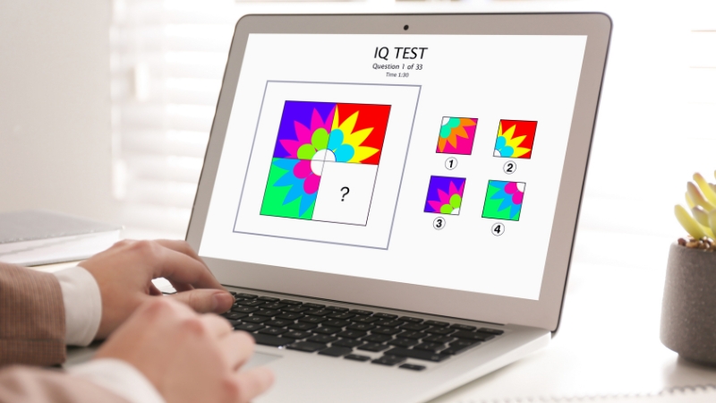 Person uses a laptop to solve a colorful IQ test puzzle with multiple choice answers