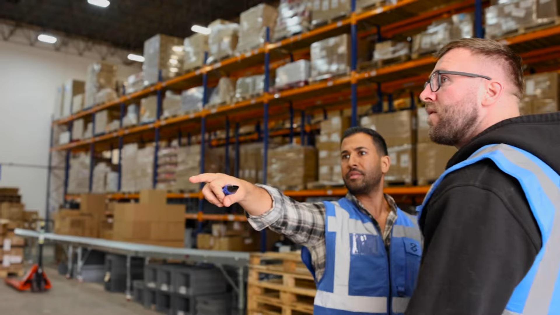 Two warehouse workers inspecting stocked shelves in a fulfillment center.