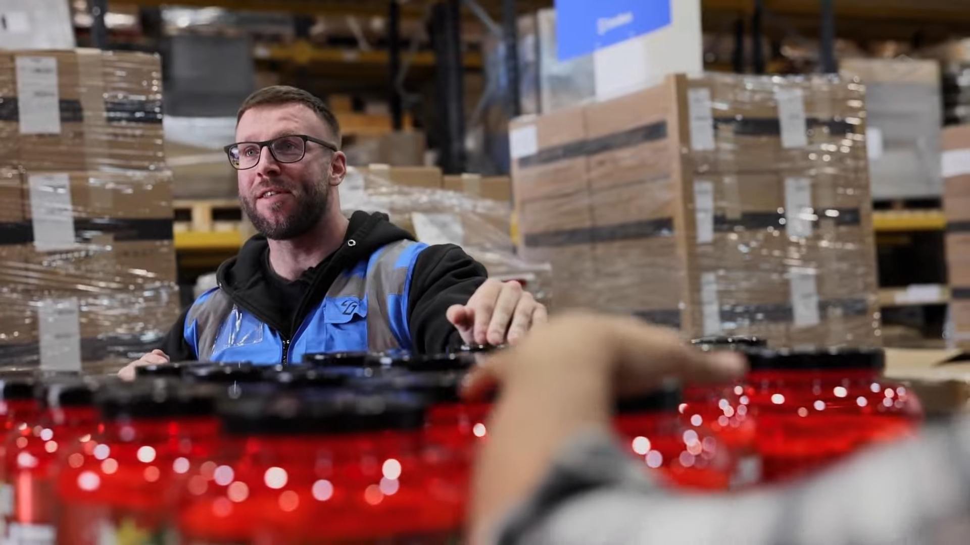 Warehouse worker passing packaged products to a colleague.