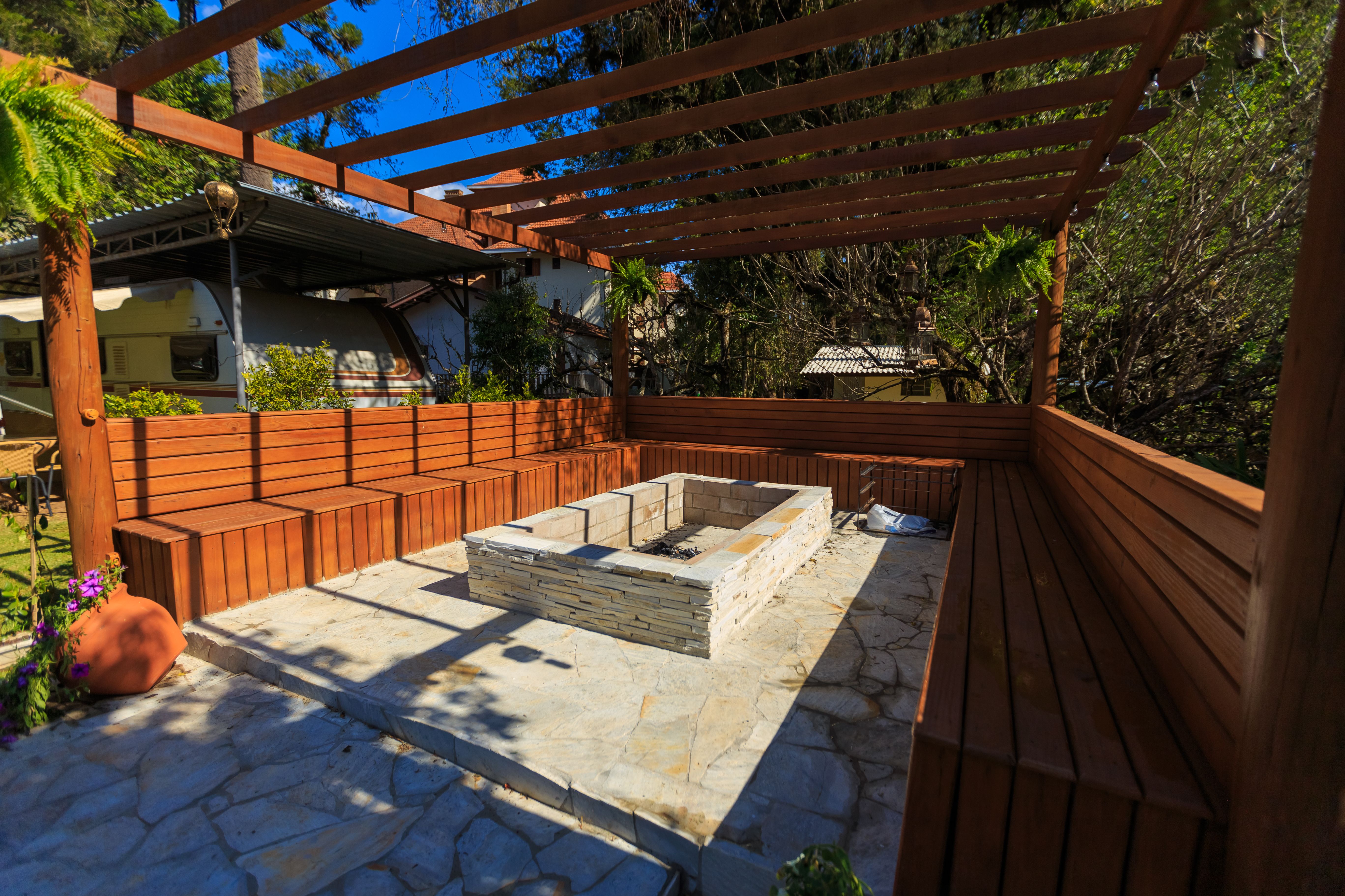 Inviting backyard patio with a stone fire pit and benches beneath a pergola