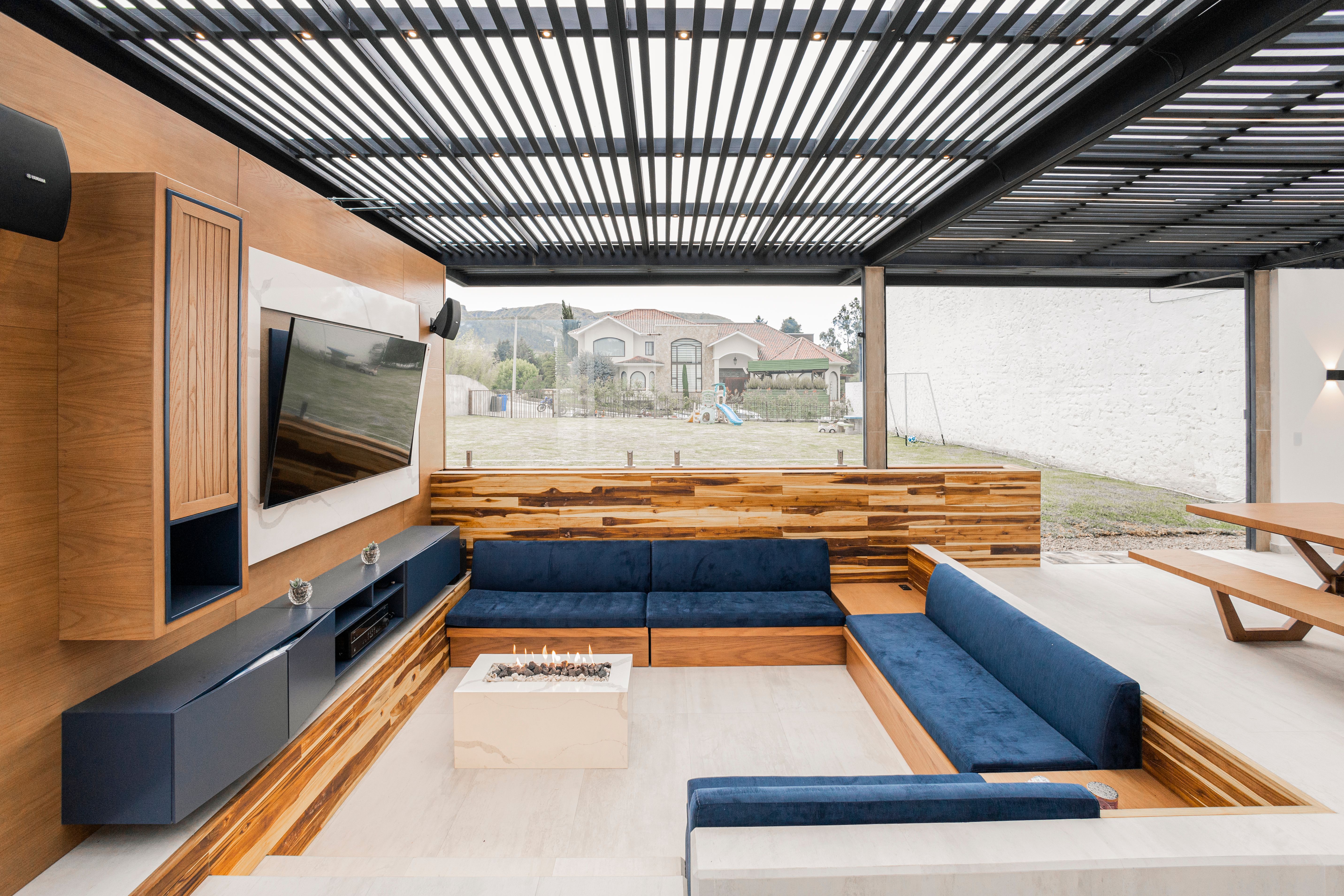 Contemporary outdoor living room with blue sofa, wood accents, and glass wall
